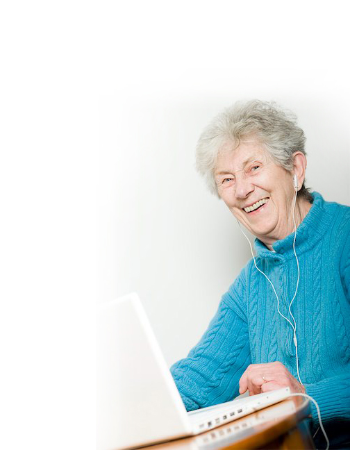 Elderly woman on a computer with headphones on. 